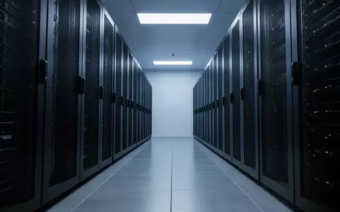 Ein moderner, minimalistischer Serverraum mit dunklen Metall-Serverracks in einer kühlen, blau beleuchteten Industrieumgebung. - Foto: über boerse-global.de