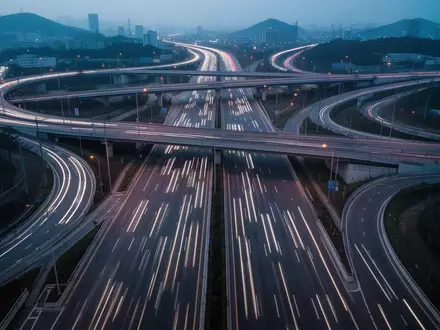Ein weitläufiges Autobahnkreuz bei Dämmerung mit klaren Fahrbahnmarkierungen und geschwungenen Kurven in einer urbanen Umgebung. - Foto: über boerse-global.de