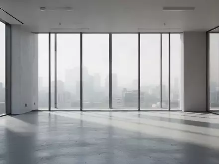 Ein minimalistischer, leerer Büro-Innenraum mit natürlichem Lichteinfall und langen Schatten auf einem Betonboden. - Foto: über boerse-global.de