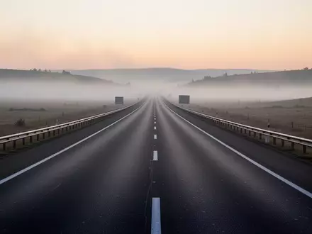 Eine leere Autobahn bei nebligem Morgengrauen erstreckt sich durch eine weite Landschaft. - Foto: über boerse-global.de
