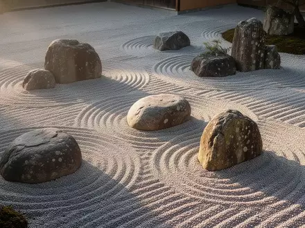 Ein minimalistischer Zen-Garten mit geharktem Kies und glatten Flusssteinen im sanften Morgenlicht. - Foto: über boerse-global.de