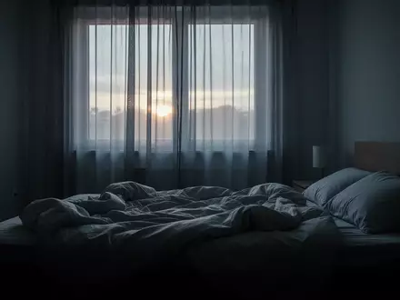 Ein ungemachtes Bett in einem spärlich beleuchteten Schlafzimmer im frühen Morgenlicht. - Foto: über boerse-global.de