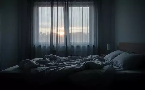 Ein ungemachtes Bett in einem spärlich beleuchteten Schlafzimmer im frühen Morgenlicht. - Foto: über boerse-global.de