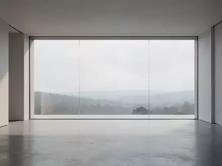 Ein minimalistischer, moderner Innenraum mit poliertem Betonboden und einer großen Glasfront mit Blick auf eine Landschaft. - Foto: über boerse-global.de