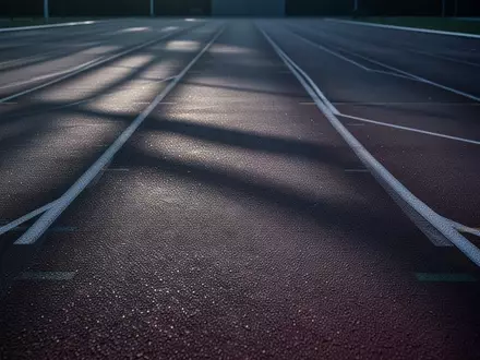 Eine leere, moderne Laufbahn bei Morgendämmerung mit langen Schatten, die eine Atmosphäre von Fokus und Energie vermittelt. - Foto: über boerse-global.de