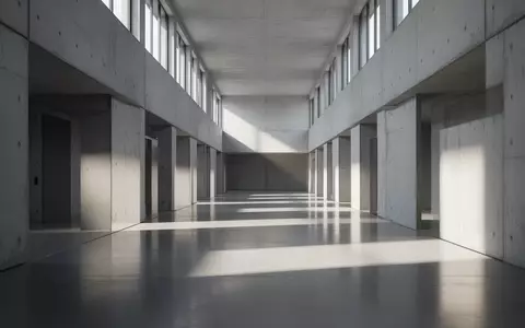 Ein minimalistischer, leerer Flur mit poliertem Betonboden und geometrischem Schattenwurf durch einfallendes Sonnenlicht. - Foto: über boerse-global.de