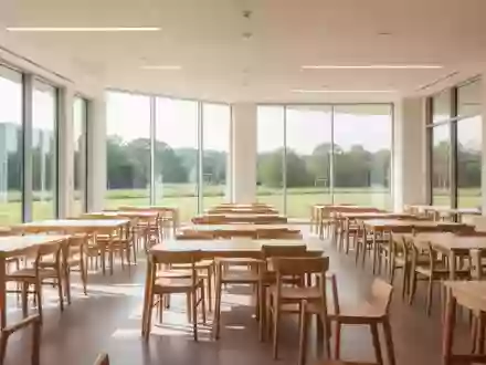 Ein heller, moderner Speisesaal in einer Bildungseinrichtung mit Holztischen und StĂĽhlen in einer sonnendurchfluteten Umgebung. - Foto: ĂĽber boerse-global.de