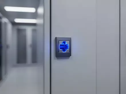 Ein blau leuchtender Netzwerkanschluss an einer Wand in einem modernen Serverraum. - Foto: über boerse-global.de