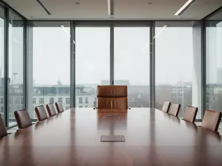 Moderner, minimalistischer Konferenzraum mit einem leeren Stuhl am Kopfende eines Tisches. - Foto: über boerse-global.de