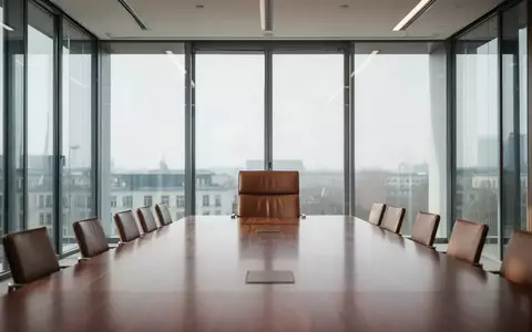 Moderner, minimalistischer Konferenzraum mit einem leeren Stuhl am Kopfende eines Tisches. - Foto: über boerse-global.de