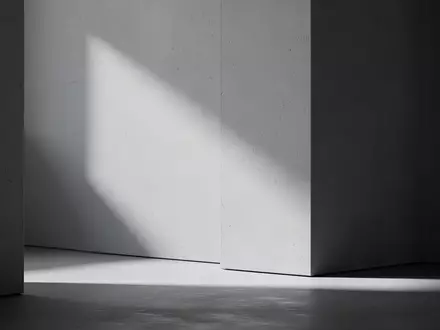 Ein minimalistischer, heller Arbeitsbereich mit klaren geometrischen Linien und natürlichem Lichteinfall auf einer strukturierten Wand. - Foto: über boerse-global.de