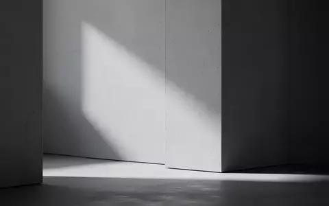 Ein minimalistischer, heller Arbeitsbereich mit klaren geometrischen Linien und natürlichem Lichteinfall auf einer strukturierten Wand. - Foto: über boerse-global.de