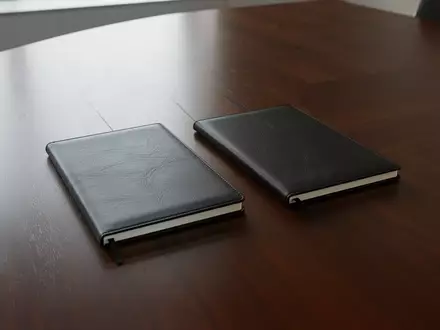 Zwei nebeneinander liegende, leere Notizbücher auf einem modernen Konferenztisch, die die rechtliche Trennung zwischen Gesellschafter und Gesellschaft symbolisieren. - Foto: über boerse-global.de