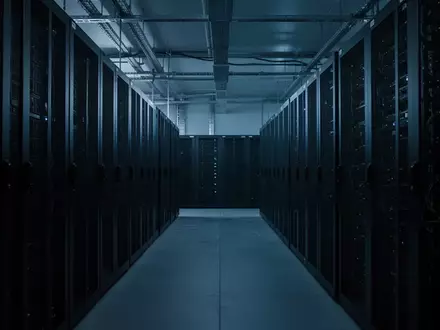 Leere, modern gestaltete Serverräume mit dunklen Serverschränken in einer kühlen, blau beleuchteten Umgebung. - Foto: über boerse-global.de