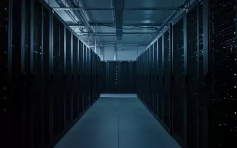 Leere, modern gestaltete Serverräume mit dunklen Serverschränken in einer kühlen, blau beleuchteten Umgebung. - Foto: über boerse-global.de