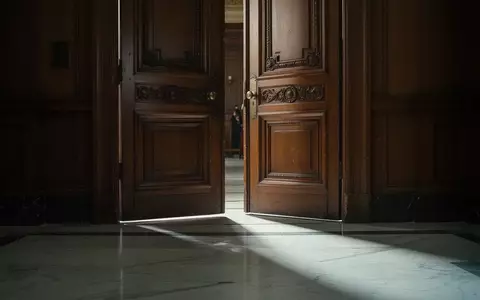 Eine schwere Holztür in einem Gerichtssaal mit einfallendem Licht auf einem Marmorboden. - Foto: über boerse-global.de