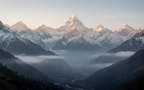 Eine weite, friedliche Berglandschaft im Himalaya bei Sonnenaufgang mit schneebedeckten Gipfeln und nebelverhangenen Tälern. - Foto: über boerse-global.de