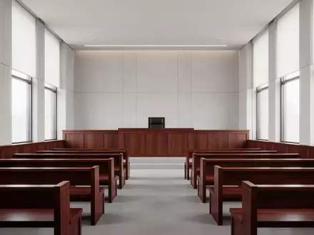 Ein leerer, minimalistischer Gerichtssaal mit polierten Holzbänken und einem Richterpult in natürlichem Licht. - Foto: über boerse-global.de
