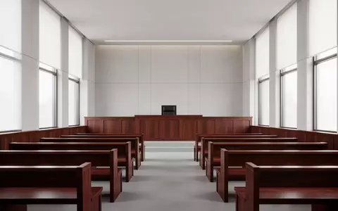 Ein leerer, minimalistischer Gerichtssaal mit polierten Holzbänken und einem Richterpult in natürlichem Licht. - Foto: über boerse-global.de