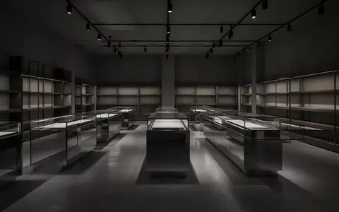 Ein leerer, minimalistischer Verkaufsraum mit Glasvitrinen und Regalen in einer gedimmten, atmosphärischen Beleuchtung. - Foto: über boerse-global.de