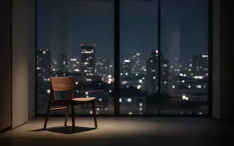 Ein minimalistisch eingerichteter Raum bei Nacht mit Blick auf ein verschwommenes, beleuchtetes Stadtpanorama. - Foto: über boerse-global.de