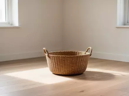 Ein leerer geflochtener Korb in einem aufgeräumten, lichtdurchfluteten Zimmer mit hellem Holzfußboden. - Foto: über boerse-global.de