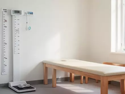 Ein helles, modernes Behandlungszimmer in einer Kinderarztpraxis mit einer Wandmesslatte und einer Untersuchungsliege. - Foto: über boerse-global.de