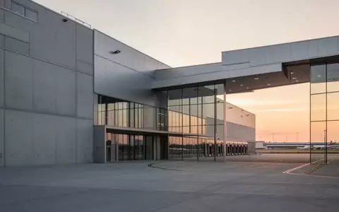 Moderne Logistikhalle mit klaren architektonischen Linien und Glasfassade in der Abenddämmerung. - Foto: über boerse-global.de