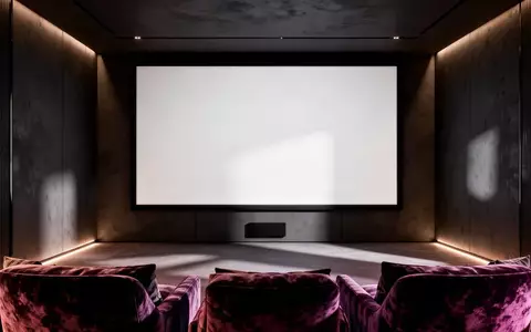Ein minimalistischer Heimkinoraum mit einer großen, leeren Projektionsleinwand an einer dunklen Wand. - Foto: über boerse-global.de