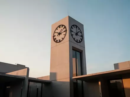 Minimalistische Architektur eines Uhrturms vor einem klaren Himmel als Symbol für Zeit und demografischen Wandel. - Foto: über boerse-global.de