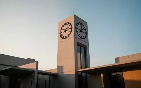 Minimalistische Architektur eines Uhrturms vor einem klaren Himmel als Symbol für Zeit und demografischen Wandel. - Foto: über boerse-global.de