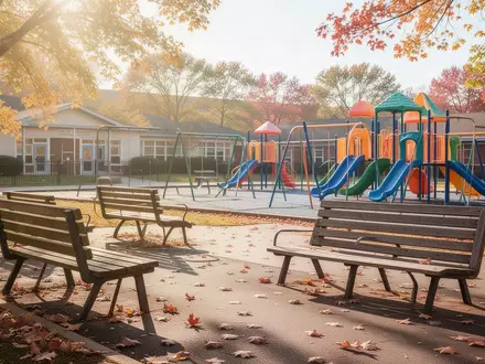 Ein sonniger, leerer Schulhof mit Spielgeräten und Holzbänken an einem Herbsttag. - Foto: über boerse-global.de