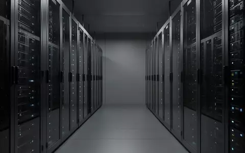 Ein moderner Serverraum mit ordentlich aufgereihten, dunklen Metall-Serverracks und dezenter, kühler LED-Beleuchtung. - Foto: über boerse-global.de