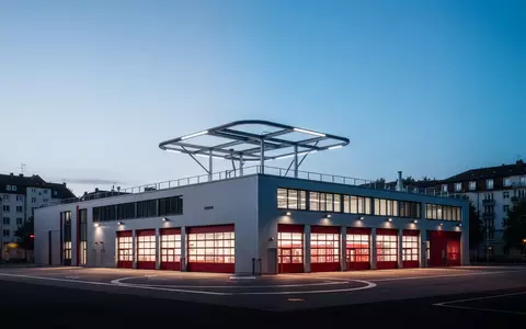 Modernes Flachdach-Gebäude einer Feuerwache in der Dämmerung mit einem Hubschrauberlandeplatz auf dem Dach. - Foto: über boerse-global.de