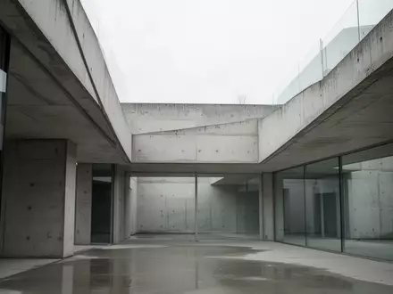 Moderne, minimalistische Architektur aus Beton und Glas bei diffusem Tageslicht, die eine sachliche und nüchterne Atmosphäre vermittelt. - Foto: über boerse-global.de