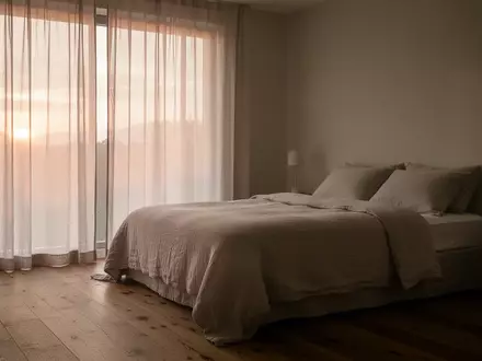 Ein minimalistisch eingerichtetes, ruhiges Schlafzimmer bei Tagesanbruch mit sanftem, natürlichem Licht. - Foto: über boerse-global.de