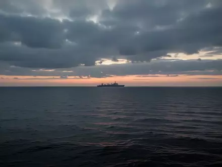 Ruhige Ostsee vor einer Küstenlinie unter bewölktem Himmel bei Dämmerung. - Foto: über boerse-global.de
