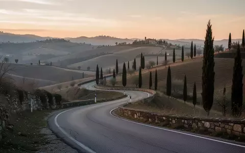 Eine kurvenreiche Landstraße in einer hügeligen italienischen Landschaft bei Tagesanbruch. - Foto: über boerse-global.de