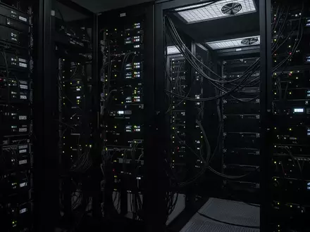 Dunkler, moderner Serverraum mit blinkenden Statuslichtern an schwarzen Hardware-Racks. - Foto: über boerse-global.de