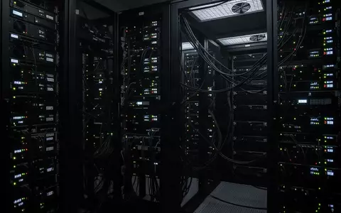 Dunkler, moderner Serverraum mit blinkenden Statuslichtern an schwarzen Hardware-Racks. - Foto: über boerse-global.de