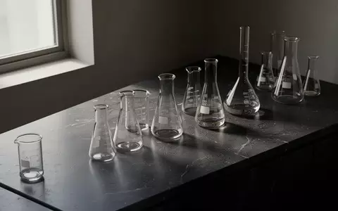 Minimalistische Laborumgebung mit Glasgefäßen auf einer dunklen, polierten Oberfläche in natürlichem Licht. - Foto: über boerse-global.de