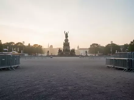 Weitläufiges, leeres Gelände der Theresienwiese in München im frühen Morgenlicht mit der Bavaria-Statue im Hintergrund. - Foto: über boerse-global.de