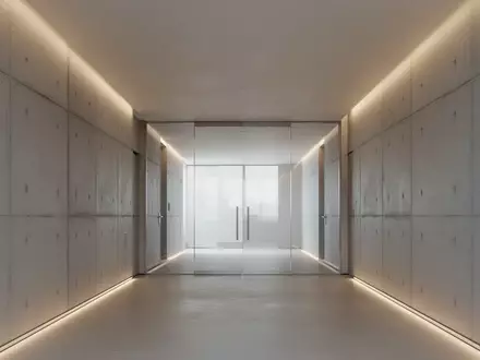 Ein minimalistischer, moderner Flur mit klaren Betonwänden und indirekter Beleuchtung, der eine Atmosphäre von Ordnung und Prüfung vermittelt. - Foto: über boerse-global.de