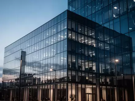Moderne Glasfassade eines Bürogebäudes in der Abenddämmerung als Symbol für Kapitalbewegungen am Finanzmarkt. - Foto: über boerse-global.de