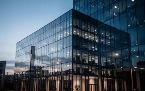 Moderne Glasfassade eines Bürogebäudes in der Abenddämmerung als Symbol für Kapitalbewegungen am Finanzmarkt. - Foto: über boerse-global.de
