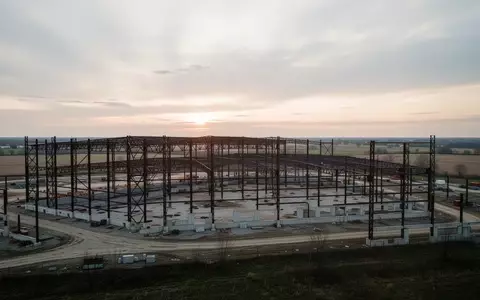 Große, im Bau befindliche Industriehalle in Ohio bei Sonnenaufgang mit Stahlgerüsten vor weitem Horizont. - Foto: über boerse-global.de