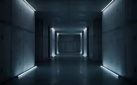Ein minimalistischer, dunkel beleuchteter Flur mit kühlem blauen Licht auf Betonoberflächen als Metapher für digitale Bedrohungen. - Foto: über boerse-global.de