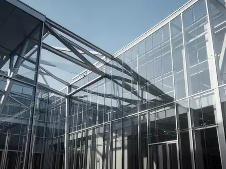 Moderne architektonische Struktur aus Glas und Stahl vor blauem Himmel, die institutionelle Stabilität symbolisiert. - Foto: über boerse-global.de