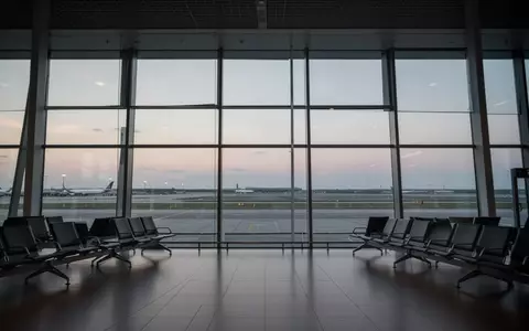 Leerer Abflugbereich eines modernen Flughafens mit Blick auf das Rollfeld bei Dämmerung. - Foto: über boerse-global.de