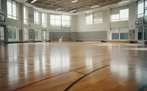 Leere, modern gestaltete Schulturnhalle mit hellen Holzböden und bunten Markierungen für Sportübungen. - Foto: über boerse-global.de